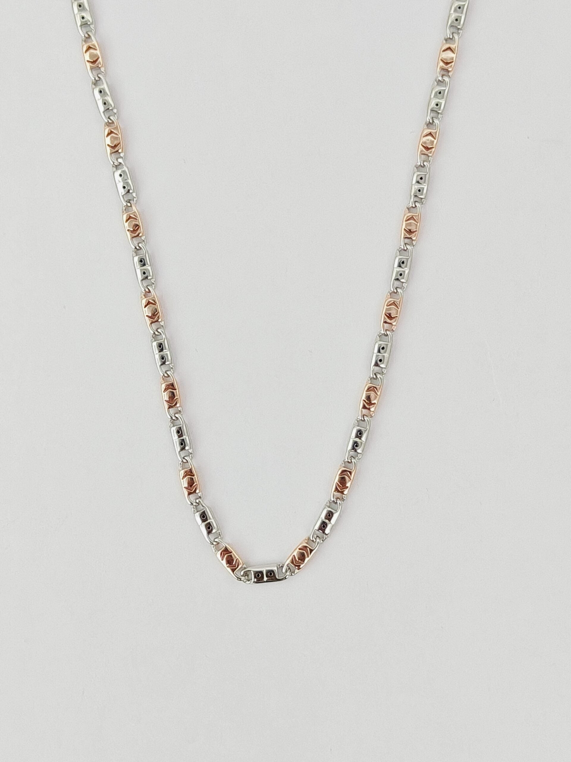 Silver and rose gold chain necklace on a light gray background